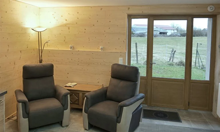 Salon du gîte, la campagne derrière la porte vitrée